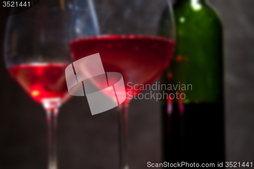 Image of red wine in two goblets and green bottle