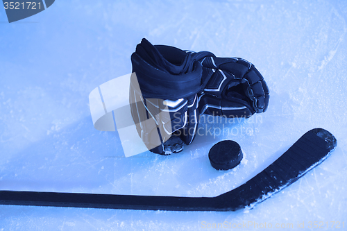 Image of hockey sticsk and puck on ice