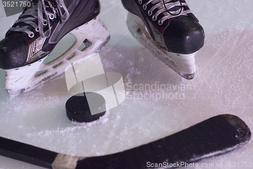 Image of hockey sticsk and puck on ice