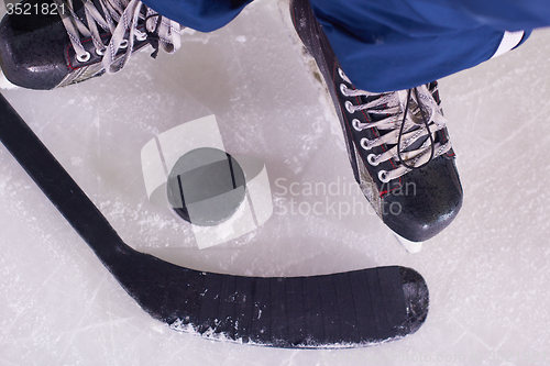 Image of hockey sticsk and puck on ice