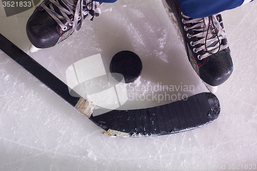 Image of hockey sticsk and puck on ice