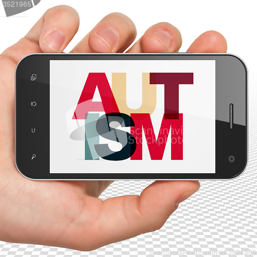 Image of Healthcare concept: Hand Holding Smartphone with Autism on  display