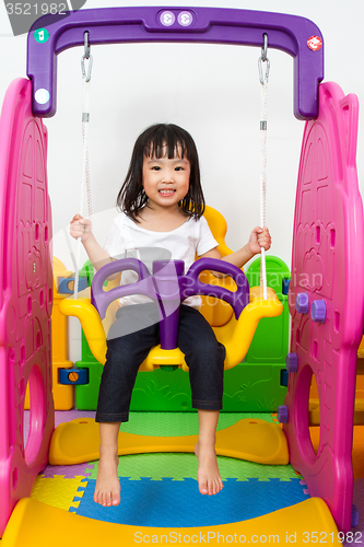 Image of Asian Chinese little girl playing on swing