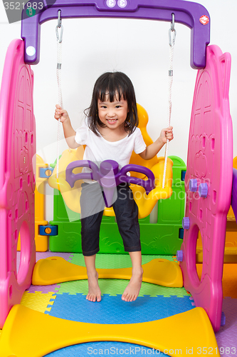 Image of Asian Chinese little girl playing on swing