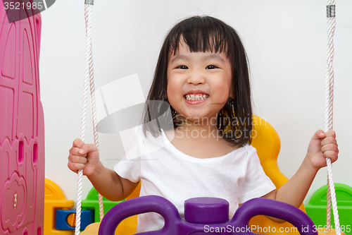 Image of Asian Chinese little girl playing on swing