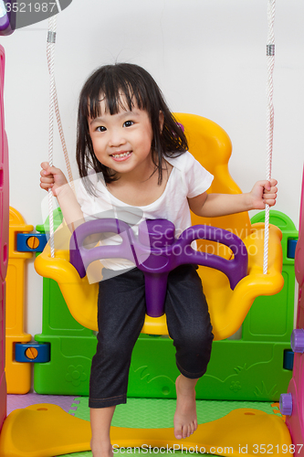 Image of Asian Chinese little girl playing on swing