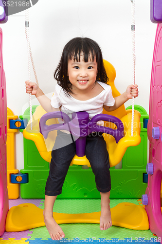 Image of Asian Chinese little girl playing on swing