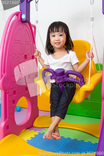 Image of Asian Chinese little girl playing on swing
