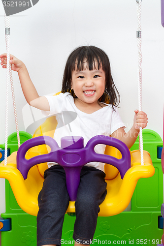 Image of Asian Chinese little girl playing on swing