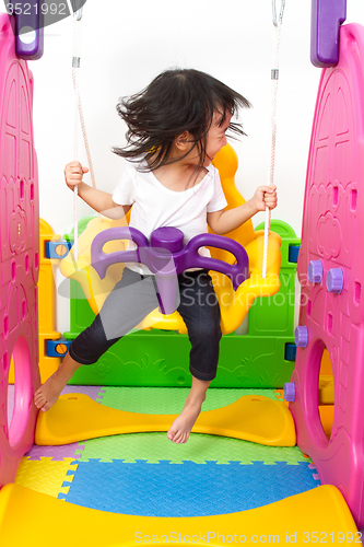 Image of Asian Chinese little girl playing on swing