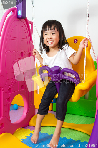 Image of Asian Chinese little girl playing on swing