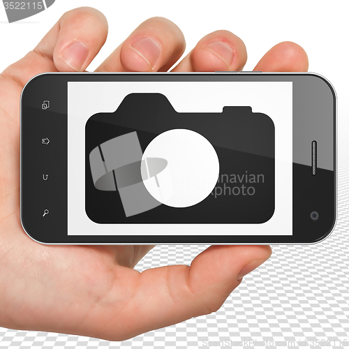 Image of Travel concept: Hand Holding Smartphone with Photo Camera on display