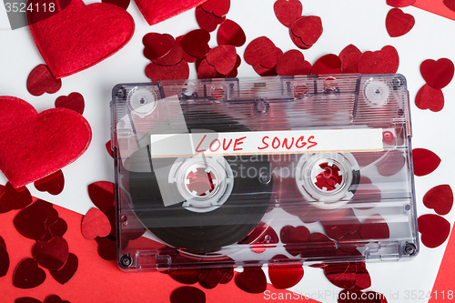 Image of Audio cassette tape on red background with fabric heart