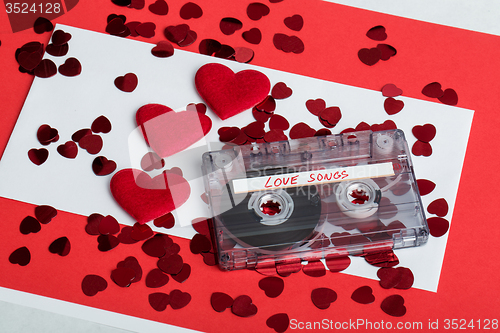 Image of Audio cassette tape on red background with fabric heart