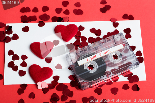 Image of Audio cassette tape on red background with fabric heart