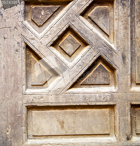 Image of nail dirty stripped paint in the brown wood door and rusty yello