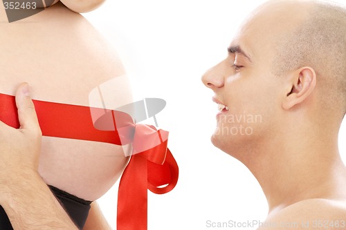 Image of proud father and belly with red ribbon