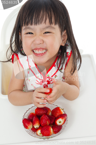 Image of Asian Chinese little girl eating strawberries