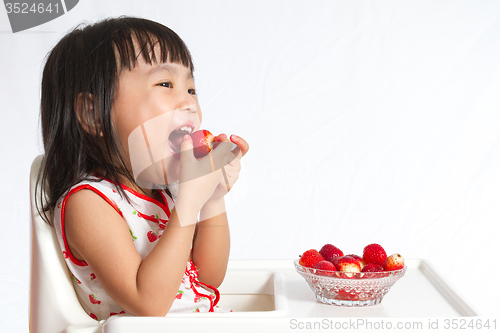 Image of Asian Chinese little girl eating strawberries