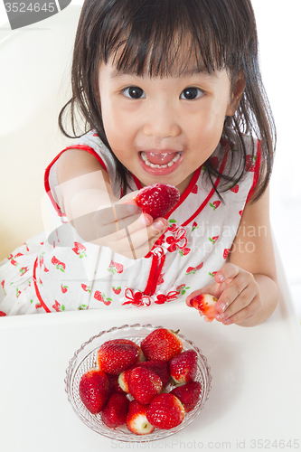 Image of Asian Chinese little girl eating strawberries