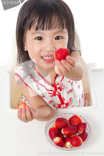 Image of Asian Chinese little girl eating strawberries