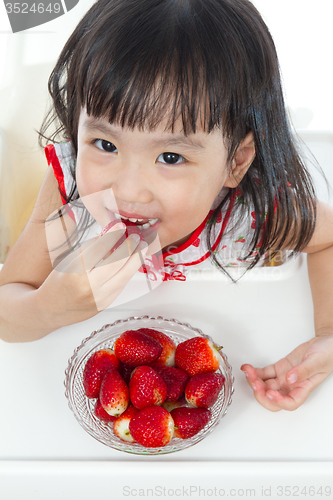 Image of Asian Chinese little girl eating strawberries