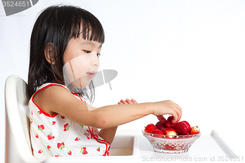 Image of Asian Chinese little girl eating strawberries