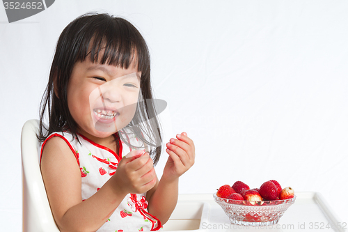 Image of Asian Chinese little girl eating strawberries