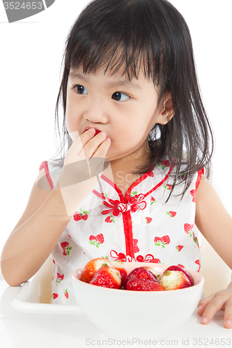 Image of Asian Chinese little girl eating strawberries