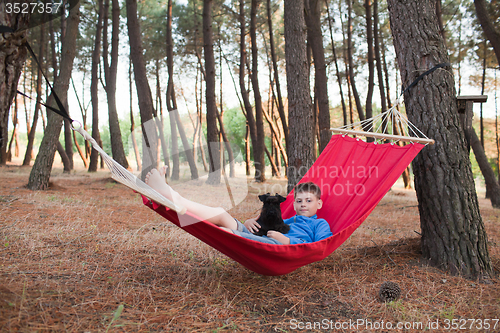 Image of Boy and his dog relaxing in hammock