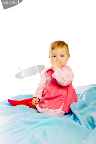 Image of Beautiful baby sitting on a blue blanket. Studio