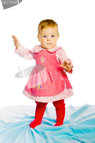 Image of baby girl standing on a blue blanket. Studio photo