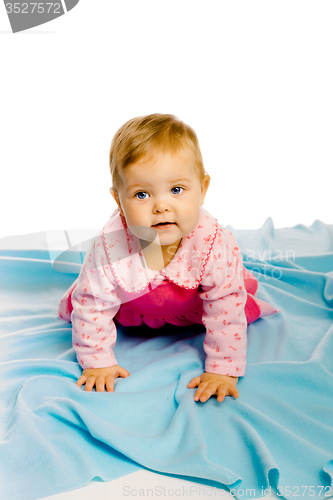 Image of baby girl crawling on the blue coverlet. Studio