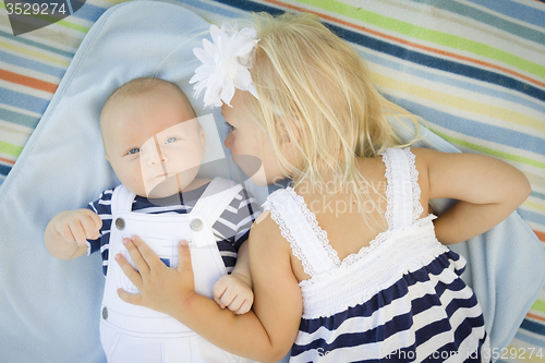 Image of Little Sister Laying Next to Her Baby Brother on Blanket