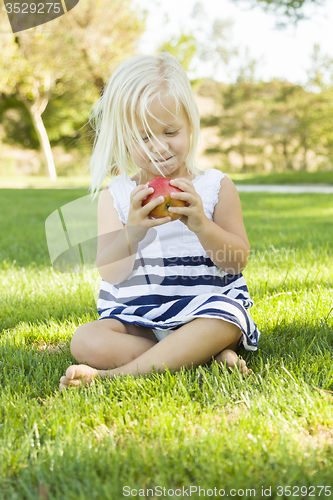 Image of Little Girl Sitting and Eating Apple Outside