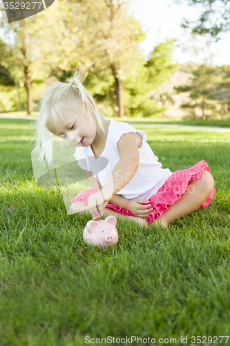 Image of Little Girl Having Fun with Her Piggy Bank Outside