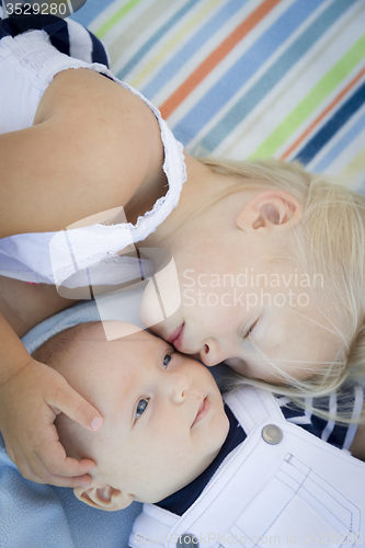 Image of Little Sister Laying Next to Her Baby Brother on Blanket