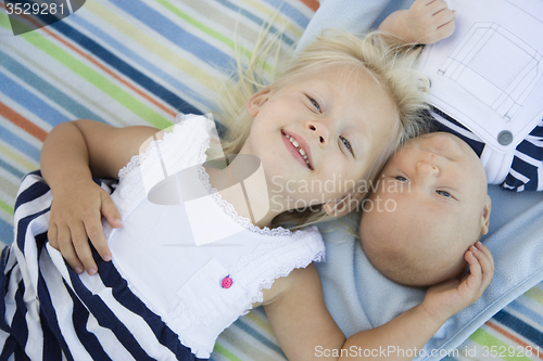 Image of Little Sister Laying Next to Her Baby Brother on Blanket