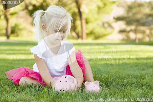 Image of Little Girl Having Fun with Her Piggy Banks Outside