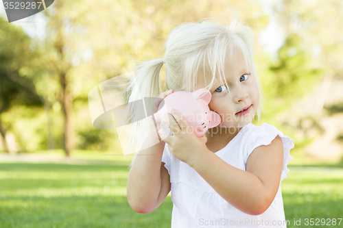 Image of Little Girl Having Fun with Her Piggy Bank Outside