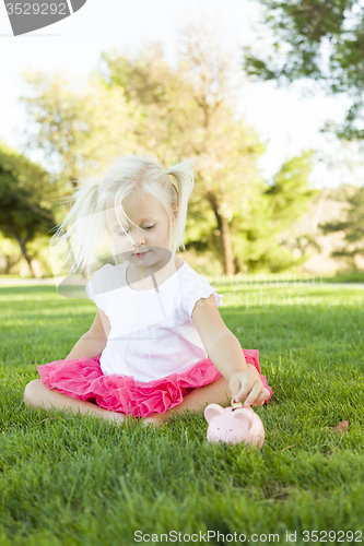 Image of Little Girl Having Fun with Her Piggy Bank Outside