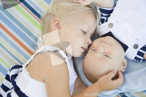 Image of Little Sister Laying Next to Her Baby Brother on Blanket