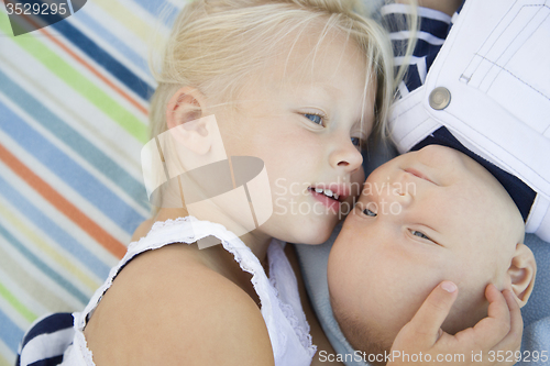 Image of Little Sister Laying Next to Her Baby Brother on Blanket