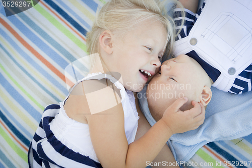 Image of Little Sister Laying Next to Her Baby Brother on Blanket