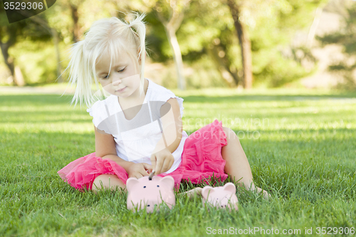 Image of Little Girl Having Fun with Her Piggy Banks Outside