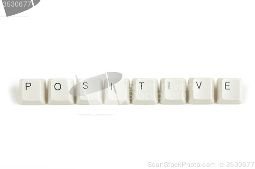 Image of positive from scattered keyboard keys on white