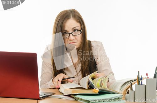 Image of Frustrated teacher is looking for something in a book