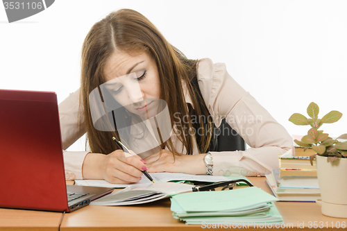 Image of Tired teacher checks students notebooks