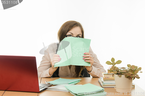 Image of The teacher covered his face with a notebook