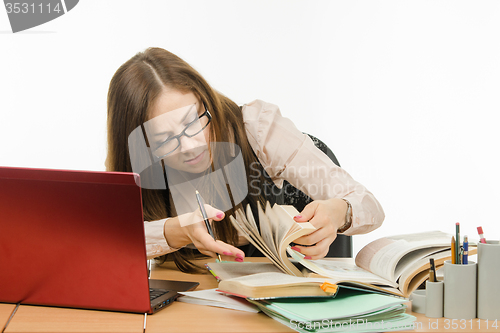 Image of Teacher leafing through a book to find information